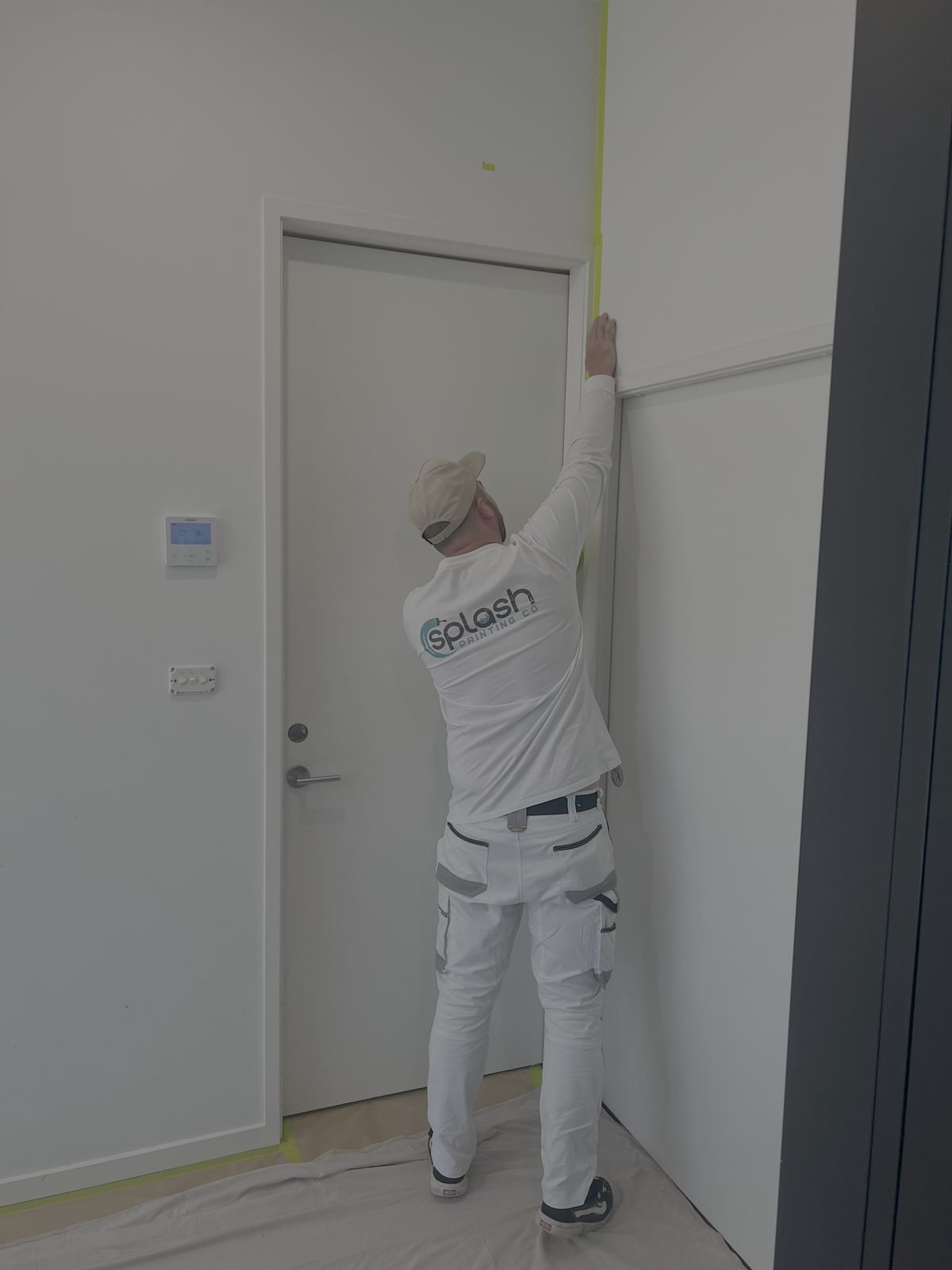 A Splash Painting Co. painter taping off a doorframe before painting